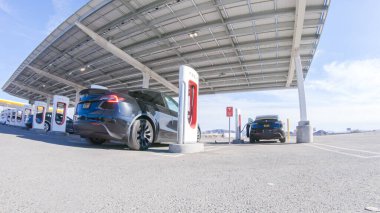 Baker, California, ABD-3 Aralık 2022-Gün boyunca Tesla bir süper şarj istasyonunda yüksek hızlı şarj altyapısını uygun ve verimli bir şekilde kullanan bir Tesla aracı görüldü.