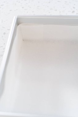 Çikolatalı şam fıstıklı şekerleme hazırlamak için parşömen kağıdıyla kare çizgili cheesecake tavası..