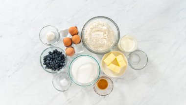 Düz yatıyordu. Limonlu yaban mersinli kek pişirmek için bardakların içindeki ölçülü malzemeler..