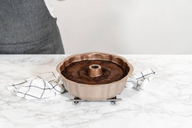 Chocolate Bundt Pastası dikkatlice tavadan çıkartılır. Yuvarlak soğutma rafına yerleştirilir. Kusursuz bir sunum ve hoş bir hoşgörü için hazırlanır..