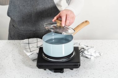Boiling water in a cooking pot to prepare chocolate pistachio fudge.