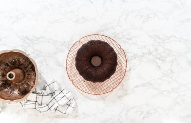 Düz yatıyordu. Chocolate Bundt Pastası dikkatlice tavadan çıkartılır. Yuvarlak soğutma rafına yerleştirilir. Kusursuz bir sunum ve hoş bir hoşgörü için hazırlanır..