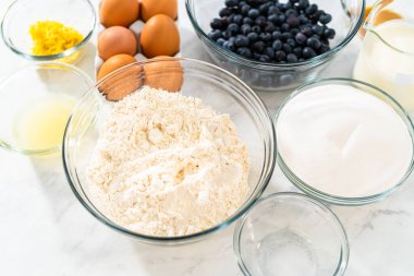 Limonlu yaban mersinli kek pişirmek için bardakların içindeki ölçülü malzemeler..