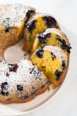 Taze pişmiş limonlu yaban mersinli kek dilimliyorum. Pudra şekerli..