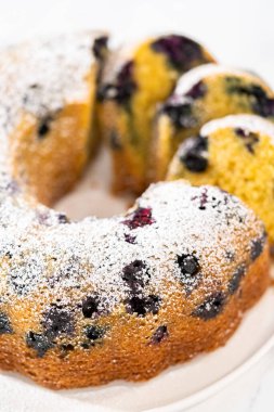 Taze pişmiş limonlu yaban mersinli kek dilimliyorum. Pudra şekerli..