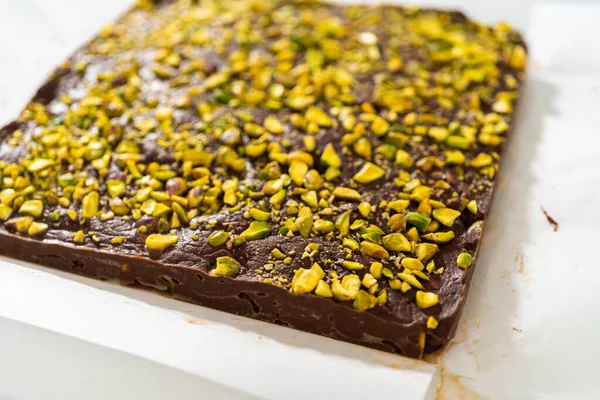 Removing Chocolate Pistachio Fudge Square Cheesecake Pan Lined Parchment — Stock Photo, Image