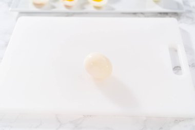 Beyaz bir kesme tahtasında haşlanmış yumurta dilimlemek..