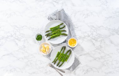 Düz yatıyordu. Sarımsaklı ıstakoz kuyruğu, haşlanmış kuşkonmaz ve beyaz tabakta limon dilimleri..