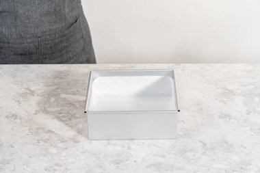 Kızılcık fıstıklı şekerleme hazırlamak için parşömen kağıdıyla kaplı kare cheesecake tavası..