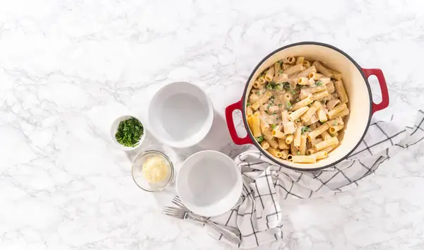 Flat lay. Chicken alfredo pasta with green peas and rigatoni pasta in a small bowl.
