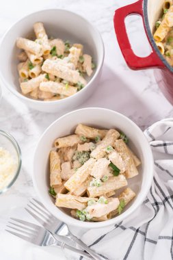 Küçük bir kasede yeşil bezelyeli tavuk ve rigatoni makarna..