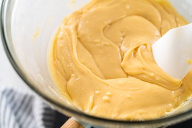 Eriyen beyaz çikolata parçacıkları ve diğer malzemeler kaynamış suyun üzerinde karışıp kızılcık fıstıklı şekerleme hazırlıyor..