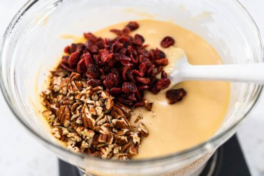 Melting white chocolate chips and other ingredients in a glass mixing bowl over boiling water to prepare white chocolate cranberry pecan fudge. clipart