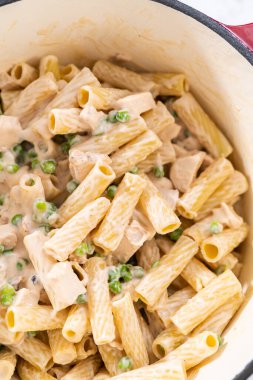 Alfredo soslu tavuk pişirmek için mayalı bir fırının içindekileri karıştırıyorum..