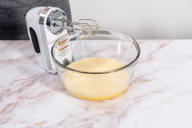 Elmalı Sharlotka keki pişirmek için karışımı büyük bir bardakta karıştırıyorum..