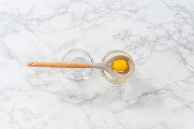 Flat lay. Separating egg whites and egg yolks with slotted spoon into small bowls.