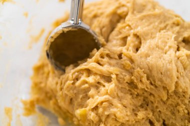 Kurabiye hamuru kepçesiyle kurabiye hamuru pişirip parşömen kağıdıyla kaplanmış bir tepsiye koyup muzlu kurabiyeleri çikolatalı çiselemek..