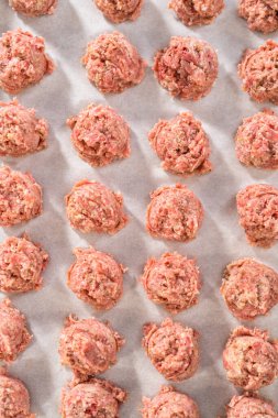 Fırında pişmiş köfte hazırlamak için parşömen kağıdıyla kaplı hamur kepçesiyle kıyma kepçesi yapmak..