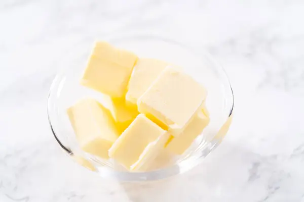 小さなガラス混合ボウルにバターのキューブ状の棒 — ストック写真