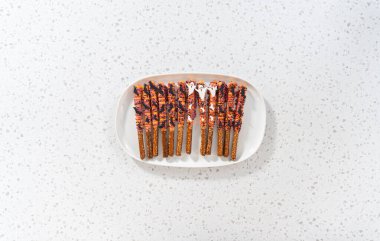 Düz yatıyordu. Cadılar Bayramı çikolata kaplı çubuk çubuklar beyaz servis tabağına serpiştirilmiş.