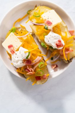 Pressure Cooker Baked Potatoes. Garnished large baked potatoes with butter, sour cream, cheese, and bacon bits on a white plate.