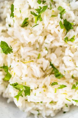 Cilantro Lime Rice. Beyaz seramik kaselerde taze maydanozla süslenmiş kişniş limonlu pirinç servis ediliyor..