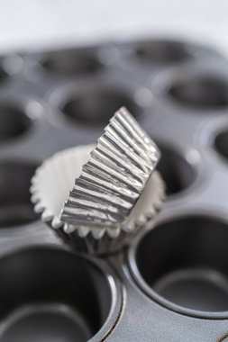 Scooping cupcake batter with dough scoop into a baking pan with liners to bake American flag mini cupcakes.