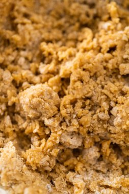 Islak ve kuru malzemelerle karıştırılmış cam bir kabın içinde çırpılmış beyaz çikolatalı makadamia fındığı..