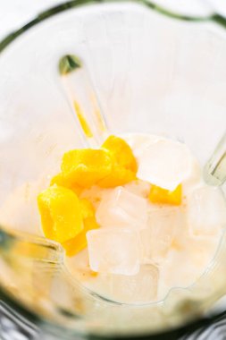 Mutfak blendırında mango boba smoothie hazırlamak için malzemeler karıştırılıyor.
