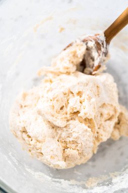 Büyük bir cam kasede ahşap bir kaşıkla karıştırılan malzemeler naan dippers pişirir..