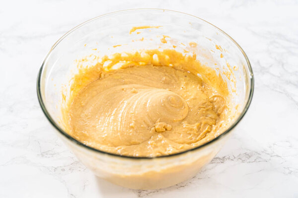 Смешивание ингредиентов с ручной смеситель в большой миске смешивания, чтобы испечь Egnog Bundt торт.