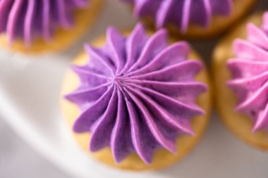 Beyaz pasta standında pembe tereyağlı taze pişmiş mini vanilyalı kekler..