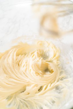 Mayasız tarçınlı çörekler için krem peynirli krema yapmak için karıştırma kabındaki malzemeleri karıştırıyorum..