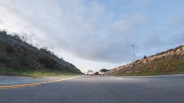Güneş batarken, Pismo Sahili yakınlarındaki HWY 101 'de Kaliforniya turuncu ve pembeye boyanmış gökyüzü ile büyüleyici bir deneyim haline gelir ve kıyı manzarası üzerine sıcak bir parıltı yayar..