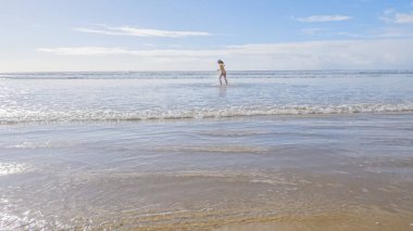 Küçük kız, soğuğa göğüs geriyor, kışın sahilde mayosuyla koşuyor..
