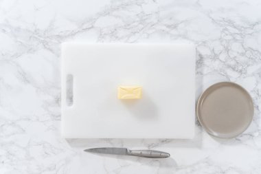 Düz yatıyordu. Beyaz bir kesme tahtasının üzerinde tuzsuz tereyağı dilimlemek.