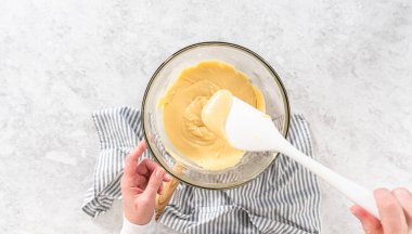 Düz yatıyordu. Eriyen beyaz çikolata parçacıkları ve diğer malzemeler kaynamış suyun üzerinde karışıp kızılcık fıstıklı şekerleme hazırlıyor..