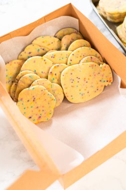 Kadın özenle, hamur karışımı şekerlemelerle dolu şekerli kurabiyeleri kırsal kahverengi bir karton kutuya yerleştiriyor..