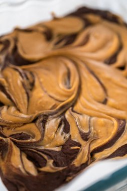 Removing chocolate fudge with peanut butter swirl from the baking pan lined with parchment