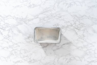 Flat lay. Greasing metal loaf baking pan to bake bread.
