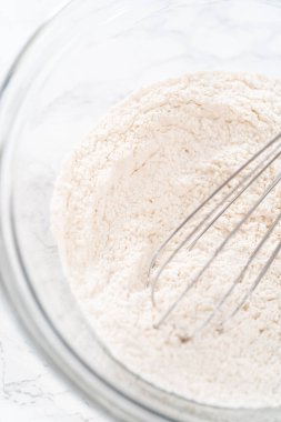 Limonlu haşhaş tohumlu kek pişirmek için bardakta çırpma kabıyla kuru malzemeyi karıştırıyorum..