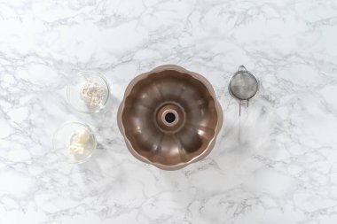 Düz yatıyordu. Kadehteki ölçülü malzemeler pişirmek için yağlanmış tavaya karıştırılıyor..