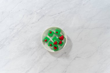 Düz yatıyordu. Beyaz tabakta kırmızı kalp parçaları olan ev yapımı çikolata yeşili şekerleme..