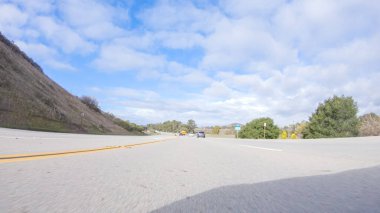 Kış günü San Luis Obispo, Kaliforniya yakınlarındaki ikonik otoyol 101 boyunca bir araba gider. Çevresindeki manzara kahverengimsi ve bastırılmış, dalgalı tepeler ve kıyı şeritleriyle