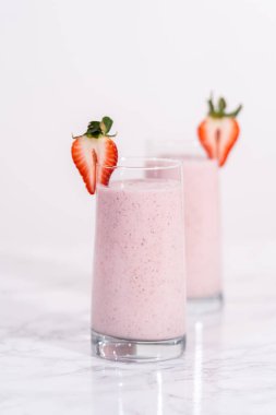 Taze taze çilek ve kağıt kamışla süslenmiş sağlıklı bir kahvaltı muzlu smoothie..