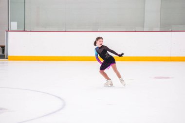 Küçük kız buz pateni pistinde artistik buz pateni yarışmasından önce pratik yapıyor..