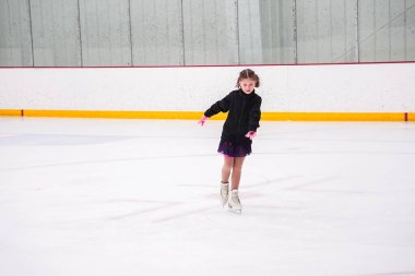 Küçük kız buz pateni pistinde artistik buz pateni yarışmasından önce pratik yapıyor..