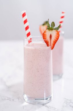 Taze taze çilek ve kağıt kamışla süslenmiş sağlıklı bir kahvaltı muzlu smoothie..