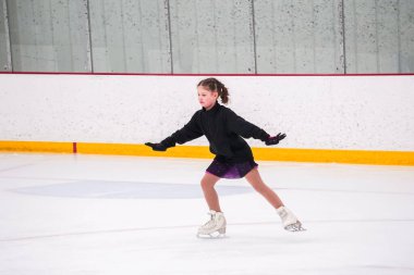 Küçük kız buz pateni pistinde artistik buz pateni yarışmasından önce pratik yapıyor..