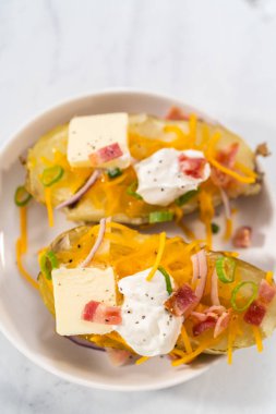 Fırında pişmiş patates. Tereyağı, ekşi krema, peynir ve pastırma parçalarıyla süslenmiş büyük fırında patates..